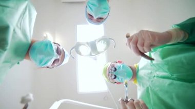 Doktor ve Hemşireler Ekibi Hasta Bakış Açısı 'nın üstünde. Operasyon görüntüsü aşağıdan. Hasta, koruyucu maskeli cerrahların yüzüne bakıyor. Hastane ameliyathanesinde çalışan grup doktoru..
