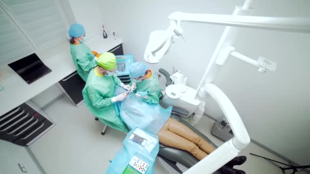Team von Zahnchirurgen führt Operationen an Zähnen durch. in einer modernen Klinik. Junge Zahnärztin. Teamwork. Zahnarzt Kieferorthopäde Chirurg, der medizinische Operationen an Wurzelkanälen durchführt. Stomatologie. Ansicht von oben