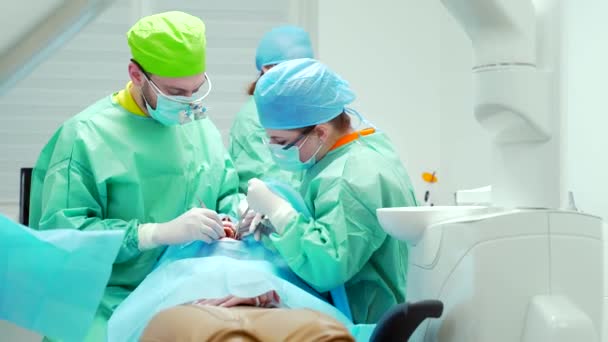 牙科医生小组对牙齿进行外科手术 在一个现代化的诊所年轻的牙医团队合作 牙科医生正牙外科医生在根管上做手术 口腔科办公室 — 图库视频影像