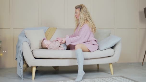 Happy Mother Lifting Baby Aiuta Figlia Sedersi Sdraiata Sul Divano — Video Stock