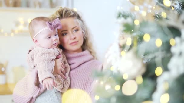 6ヶ月の小さなかわいい母親の肖像画を閉じる古い女の子は自宅でクリスマスツリーを飾る ニットセーターのブロンドのお母さんと赤ちゃんは お正月を祝います Blurred Bokeh — ストック動画
