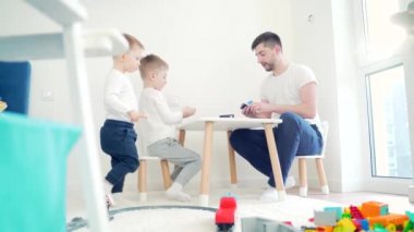 Baba ve oğul masadaki çocuk odasında masa oyunu oynuyorlar. Baba ve küçük çocuk ilginç bir oyun geliştiriyorlar. Mutlu Aile birlikte vakit geçirir. Evdeki beyaz çocuk odasında oyuncaklar