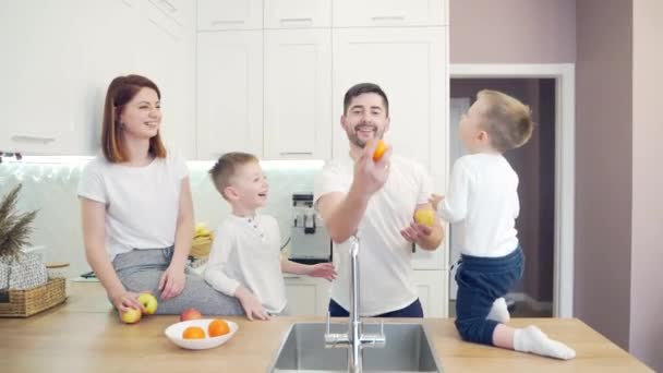 Veselá Mladá Rodina Malými Dětmi Žonglujícími Ovocem Kuchyni Dva Malí — Stock video