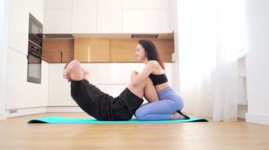 Bir çift genç sporcu evde fiziksel egzersiz yapıyor. Karın kasları üzerinde egzersiz yap yerden şınav çek ve bir öpücükle bastır. Aşık erkek ve kadın birlikte eğitim yapıyorlar. Takım