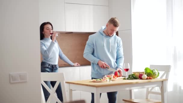 在现代厨房里 年轻有为的夫妻夫妇在一起做着健康的食物 花些时间在一起准备蔬菜沙拉和葡萄酒 快乐快乐的家庭 — 图库视频影像