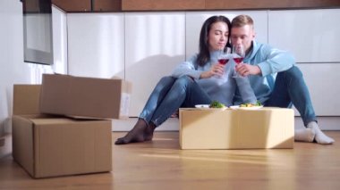 Mutlu, genç, evli bir çift, evde yeni bir daireye taşındıktan sonra karton bir kutunun üstünde şarap içip yemek yiyorlar. Yeni alınmış konutlar