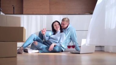 Genç ve mutlu bir aile yeni bir daireye taşınmamızı kutluyor. Kendine ait bir ev. Erkek ve kız mı yoksa elinde karton kutularla yerde oturmuş dizüstü bilgisayara bakan şarap içen kadın ve erkek mi? Evli çift yaşam tarzı