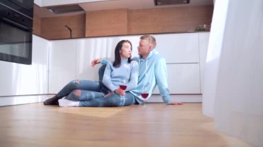 Genç, mutlu, evli bir çift yerde oturuyor. Bardakları şarapla tokuşturmak, yeni ev alımını kutlamak, başarılı mortgage yatırımları. Aile eşi flört etmekten zevk alıyor. Birlikte bir dairede vakit geçirin.