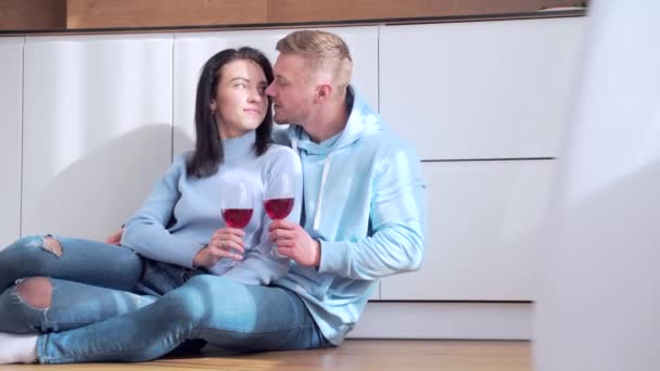 幸福的年轻夫妇坐在地板上 酒杯与酒的碰撞 庆祝新房的购买 抵押贷款投资的成功 享受约会的家庭伴侣 一起呆在公寓里 — 图库视频影像