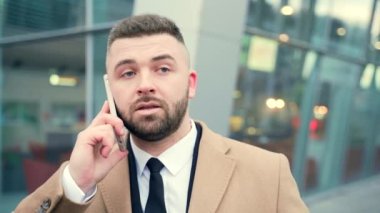 Cep telefonu ya da akıllı telefondan konuşan mutlu iş adamının portresi. Dışarıyla iletişim kuran yakışıklı erkek turistin yüzü. Modern bir havaalanı ya da şehir sokak binasının arka planında