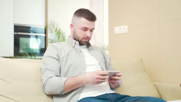 Young Adult Bearded Man Playing Game Mobile Phone Home Sitting — Stock Video