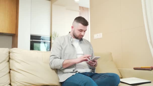 Jeune Homme Excité Avec Téléphone Mobile Assis Sur Canapé Dans — Video