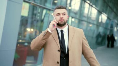 Cep telefonu ya da akıllı telefondan konuşan mutlu iş adamının portresi. Dışarıyla iletişim kuran yakışıklı erkek turistin yüzü. Modern bir havaalanı ya da şehir sokak binasının arka planında