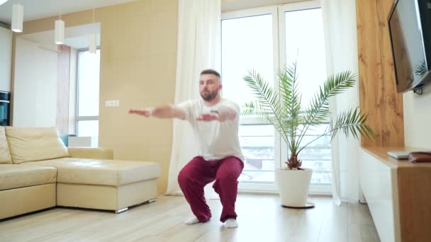 Joven Barbudo Guapo Haciendo Ejercicios Físicos Sentadillas Pijama Casa Sala — Vídeos de Stock