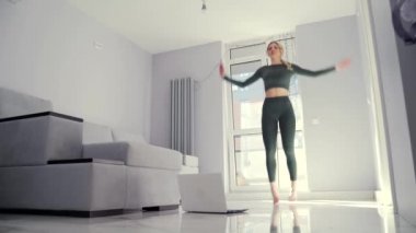 Genç, formda bir kadın evinde bilgisayar ya da dizüstü bilgisayarın önünde zıplayıp kollarını kaldırarak aerobik yapıyor. Fitness kızı, video dersleri Whit 'e çevrimiçi eğitim mesafesi yardımı yapıyor