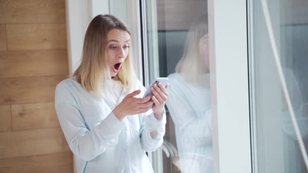 Ung Lycklig Kvinna Såg Goda Nyheterna Smartphone Står Vid Fönstret — Stockvideo