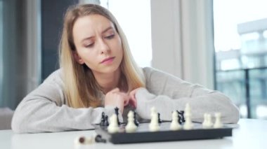 Portre genç çekici kadın internette satranç oynuyor evdeki masada dizüstü bilgisayarla. Karantina sırasındaki kadınlar internette oyun oynuyorlar..