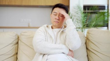 Genç Asyalı bir adam evdeki kanepede oturmuş sorunlardan ve depresyondan endişe ediyordu. Erkeklerin iş ya da aile ilişkileri, kredi geri ödeme borçlarıyla ilgili sorunları vardır.