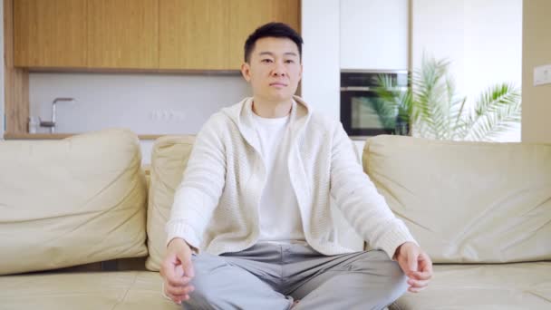 Calm Mindful Young Asian Man Sits Sofa Home His Eyes — Stock Video