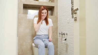 Mutlu beyaz kadın hamilelik testi pozitif çıkınca sevinçten havalara uçuyor. Evdeki kadın portresini yakından çek. Sonuçları kontrol et ve heyecanla tuvalette otur. Mutluluk