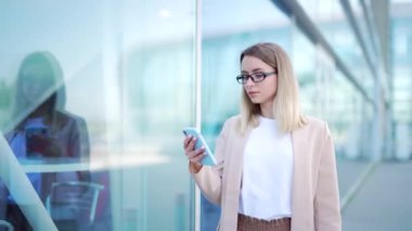 Genç bir iş kadını gider ve elinde cep telefonu kullanır. Şehir geçmişi, modern bir ofis binası. Çekici bir iş kadını ya da öğrenci kadın akıllı telefon kullanarak şehir sokaklarında yürüyor.