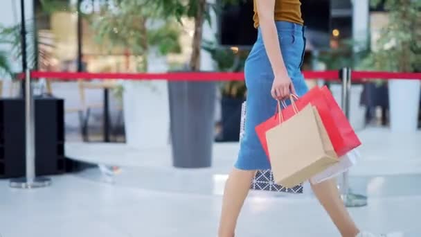 在购物中心里 穿着粗斜纹棉裙 头戴彩色礼品包装纸袋的不为人知的年轻女购物者正在走向前来 女人的腿在商店里走着呢 生活方式 — 图库视频影像