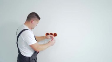 Erkek işçi, uzman elektrikçi, tamirden sonra elektrik prizi kuruyor. Adam inşaat alanındaki yeni House binasının elektrik prizi kutusunu bağlıyor.