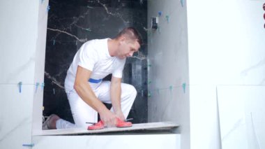 Endüstriyel tiler Profesyonel İnşaatçı döşeme tadilatı için seramik bir fayans yerleştiriyor. Ev ya da apartmanın içine fayans döşeyen adam tecrübeli bir tamirci. Bitirme çalışmaları