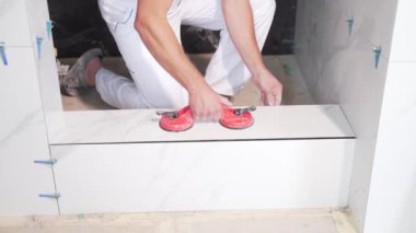 Endüstriyel tiler Profesyonel İnşaatçı döşeme tadilatı için seramik bir fayans yerleştiriyor. Ev ya da apartmanın içine fayans döşeyen adam tecrübeli bir tamirci. Bitirme çalışmaları
