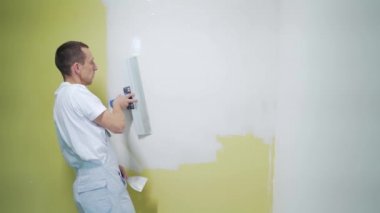 Tecrübeli bir tamirci duvarları sıva ile kaplıyor, spatula, macun bıçağı ve modern havan topu ve sıva kullanıyor. Portre profesyoneli macun sıva. Usta zanaatkar, uzman beyaz yüzey yapıyor.