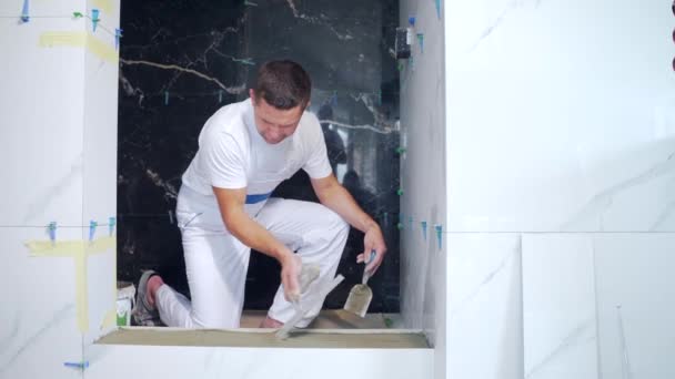 Male Worker Professional Mounts Ceramic Tile Bathroom Spatula Glue Repair — Stock Video