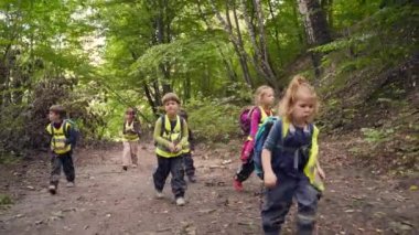 Küçük çocuklar ormanda bir yürüyüşe çıkıyorlar. Vahşi bir anaokulundan gelen çocuklar birlikte orman dağlarında yürüyüş yaparlar. Açık havada küçük bir anaokulu yürüyüşüne katılıyor. Seyahat yaz kampı.