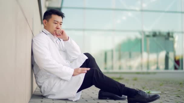 Πορτρέτο Αγχωτικό Ασιάτης Γιατρός Κάθεται Στέκεται Έξω Από Ένα Νοσοκομείο — Αρχείο Βίντεο