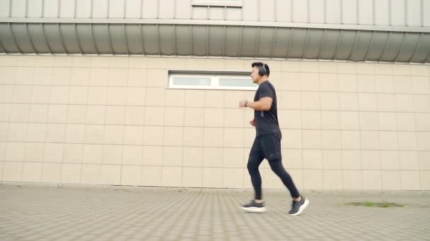 Ένας Νεαρός Ασιάτης Τρέχει Αστικό Φόντο Τοίχου Δρομέας Ακουστικά Ακούει — Αρχείο Βίντεο