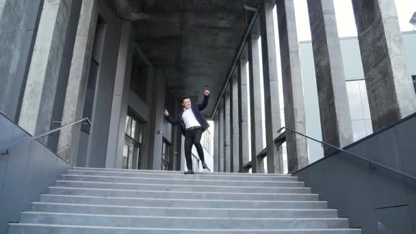 쾌활하게 아시아 사업가가 계단을 나가면서 현대식 사무실 건물을 바깥으로 밖에서 — 비디오