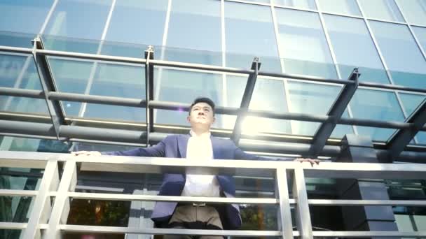 Pewny Siebie Młody Azjatycki Biznesmen Stojący Przy Poręczy Nowoczesnego Budynku — Wideo stockowe