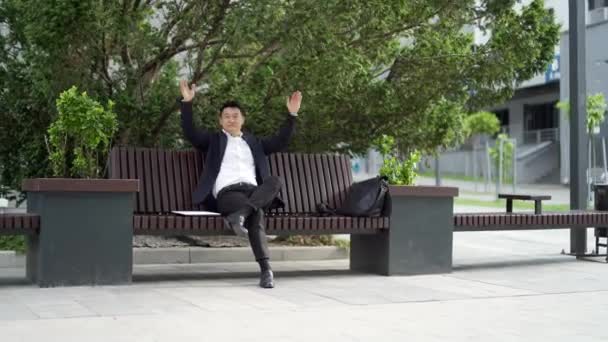 Gelukkige Aziatische Kantoormedewerker Zakenman Zittend Rustend Een Bankje Het Stadspark — Stockvideo