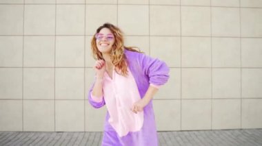 Sarı duvarda dans eden neşeli, mutlu, genç bir kadın. Tek boynuzlu at kostümlü maskeli çılgın kız. Eğlence insanları, mutluluk, neşe Şehir sokaklarında modern yaşam tarzı