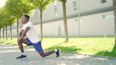 Aktif Afro-Amerikan formda adam dışarıda fiziksel egzersiz yapıyor. Spor giyinen erkek sporcu şehir parkında spor yapıyor. Dışarıda sağlıklı yaşam tarzı spor yapıyor. Koşmadan önce ısınma.