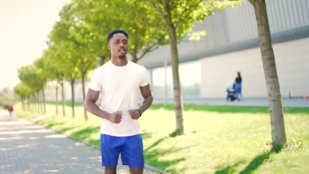 若いアフリカ系アメリカ人の男が街の公園の都市の背景で通りを走っている 朝のジョギング アクティブな健康的なライフスタイルフィットネス スポーツワークアウト屋外 アスリートトレーニング実行演習 — ストック動画