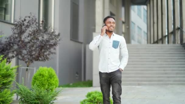 Веселый Африканский Американец Ходит Разговаривает Городской Улице Повседневной Одежде Используя — стоковое видео