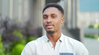 Kapalı portre mutlu Afrikalı Amerikalı adam dışarı kameraya bakıyor. Gülümseme genç, yetişkin, yakışıklı, sıradan gömlekli adam modern şehir caddesinde arka planda bulanıklaştı. Yakın çekim