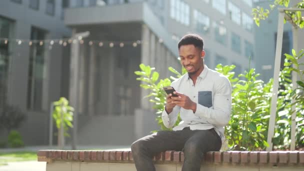 Heureux Homme Afro Américain Vêtements Décontractés Assis Sur Banc Extérieur — Video