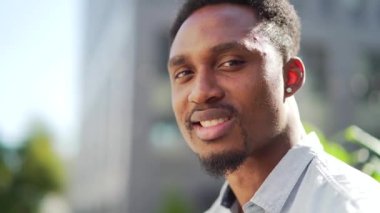 Kapalı portre mutlu Afrikalı Amerikalı adam dışarı kameraya bakıyor. Gülümseme genç, yetişkin, yakışıklı, sıradan gömlekli adam modern şehir caddesinde arka planda bulanıklaştı. Yakın çekim