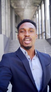 dikey görüntülü akıllı telefon kamerası Afro-Amerikan iş adamı bir video görüşmesinde ön kamera kullanarak telefonda konuşuyor. Siyah iş adamı web kamerasından konuşuyor. Takım elbiseli bir ofis çalışanının konuşması.