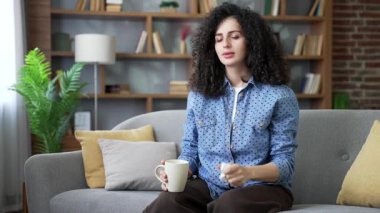 Hasta genç kadın evdeki oturma odasında kanepede otururken soğuk ve akan bir burundan muzdarip. Sağlıksız kadın burnunu mendille siliyor, sıcak bir içecek içiyor. Hasta kız grip ve virüs kapmış.