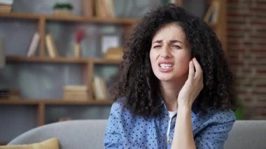 Sağlıksız genç kadın evdeki kanepede otururken kulak ağrısından muzdarip. Hasta kadın parmaklarıyla kulağına dokunuyor. Amcası, kiremitleri, egzaması, kulak hastalıkları ya da kulak iltihabı var. Kulak ağrısı. Kapat.