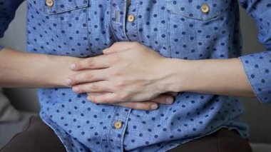 Kapatın. Karın masajı yapan kadın eller. Evde kanepede otururken karın ağrısı çeken genç bir kadın. Sıradan gömlekli bir kız zehirlenme, kabızlık, spazm ya da regl olabilir.