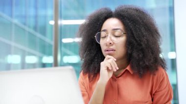 Düşünceli Afrikalı Amerikalı iş kadını iş yerindeki bilgisayarında çalışırken problem çözmeyi düşünüyor. Siyahi kadın yönetici projeyle ya da girişimle meşgul. Kapat.