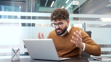 Kızgın iş adamı iş yerindeki iş yerinde dizüstü bilgisayarını kullanarak bir video görüşmesinde tartışıyor. Sinirli bir patron çevrimiçi bir konferansta astıyla tartışıyor.